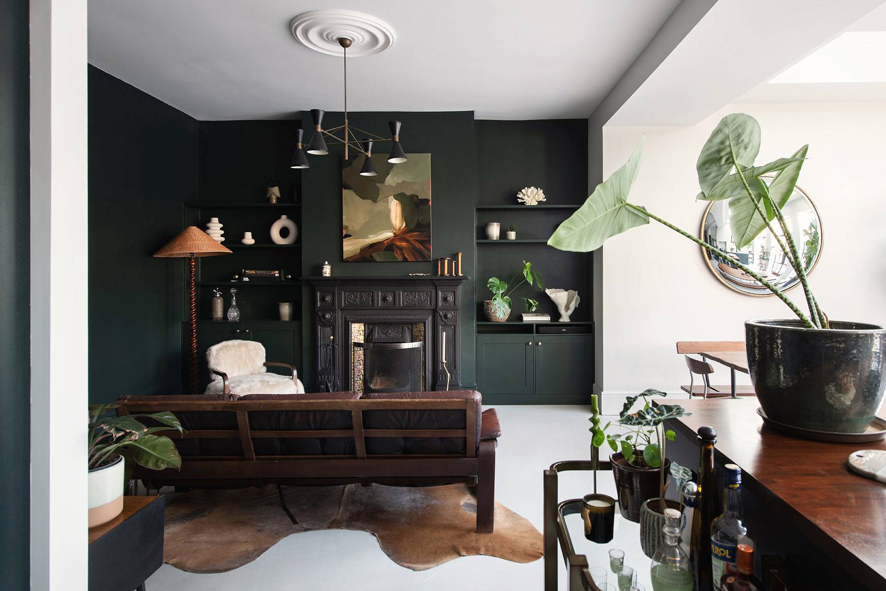 Dark forest green living room featuring a cast iron fireplace hearth, built-in shelving, and leather armchair in SW16, Love Locations.