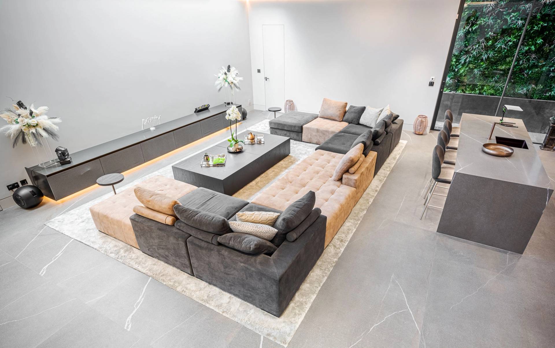 Top-down perspective of a luxury basement cinema lounge with grey sectional couch and neutral area rug, Love Locations SW11.
