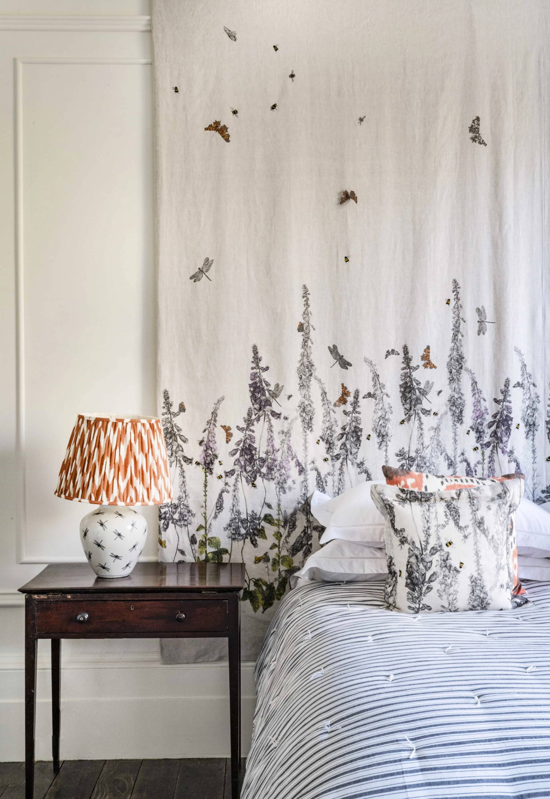 Detail of a botanical floral wall mural paired with a pleated lamp shade and wooden nightstand, Love Locations.