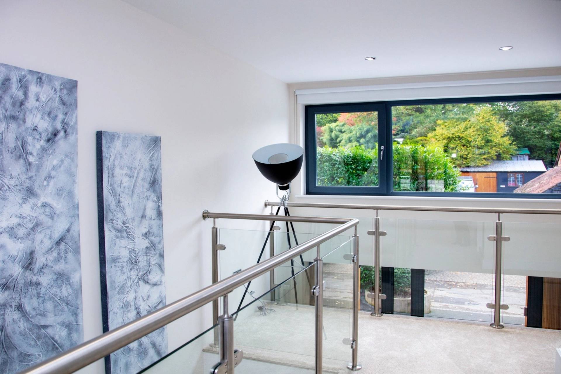 Open mezzanine landing area featuring modern glass railings and architectural spotlighting, premium residential shoot space via Love Locations.