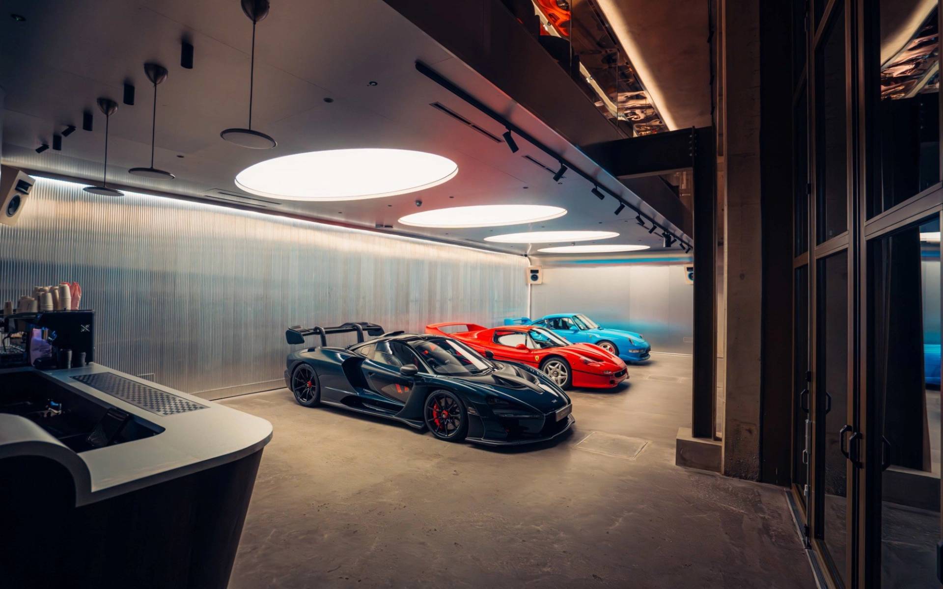 Collection of hypercars including a black Ferrari and red sports car inside Plonkers Listening Bar in Brentford TW8 via Love Locations.