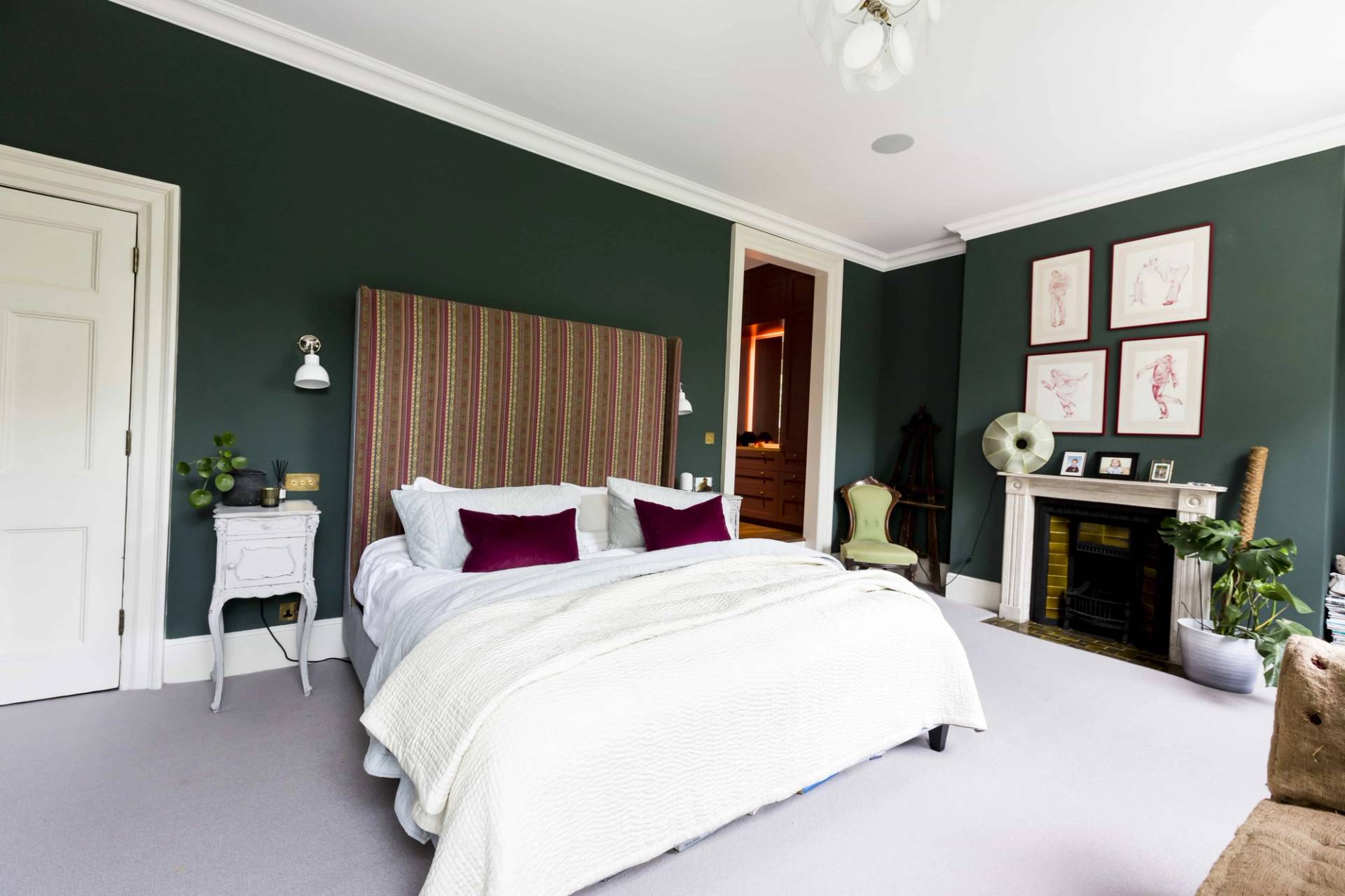 Forest green master bedroom in Camberwell, SE5 with striped headboard, white bedding, and period fireplace via Love Locations.