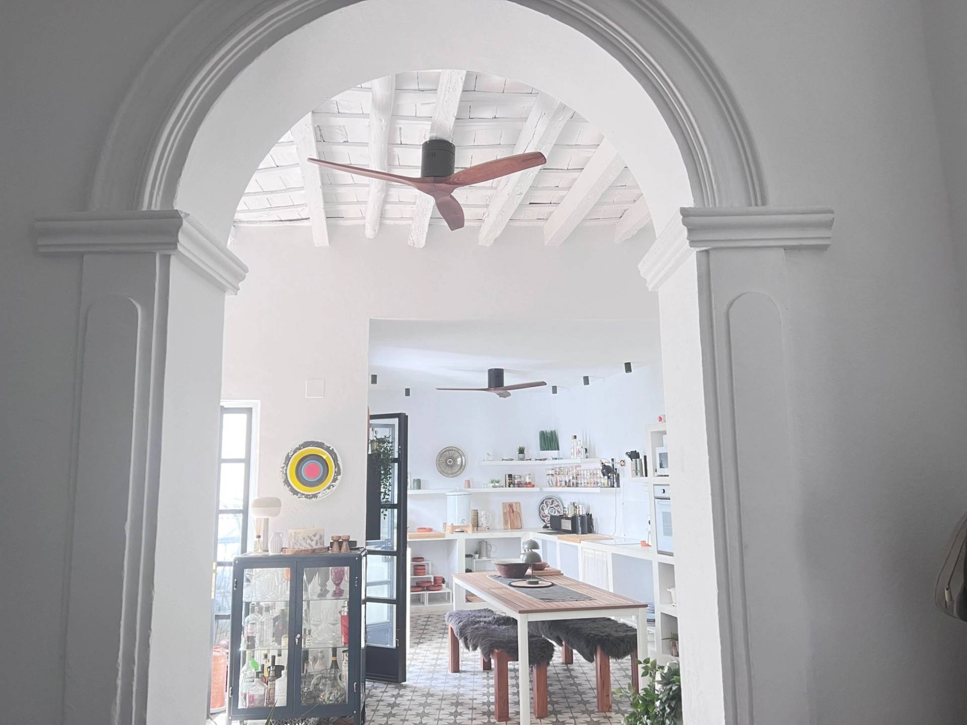 Dramatic white architectural plaster archway leading into an open dining and kitchen space in Jimena de la Frontera via Love Locations.