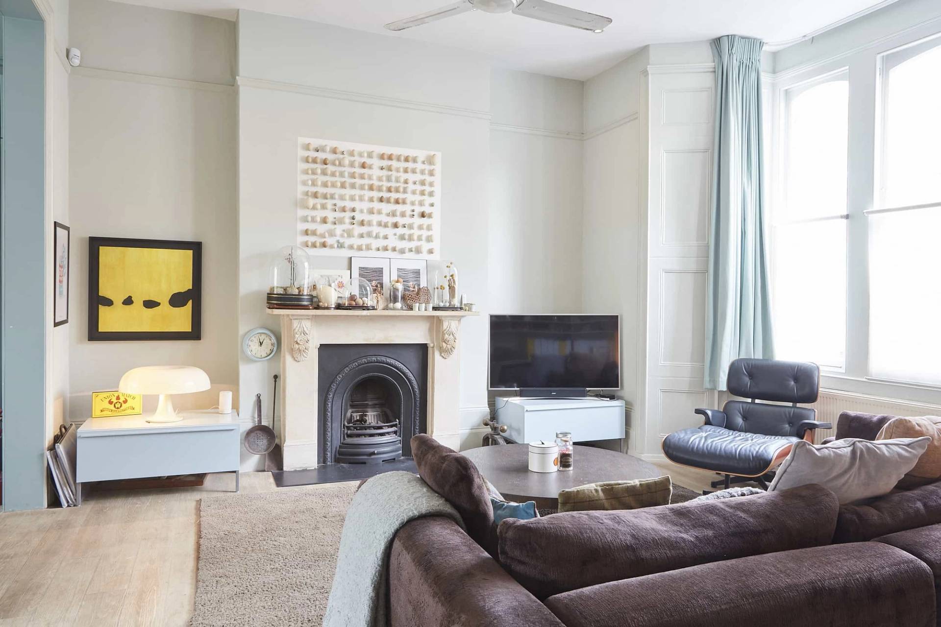 Period fireplace hearth with cast iron surround, duck-egg blue panelling, dark velvet sofa, and neutral area rug, Love Locations N5.