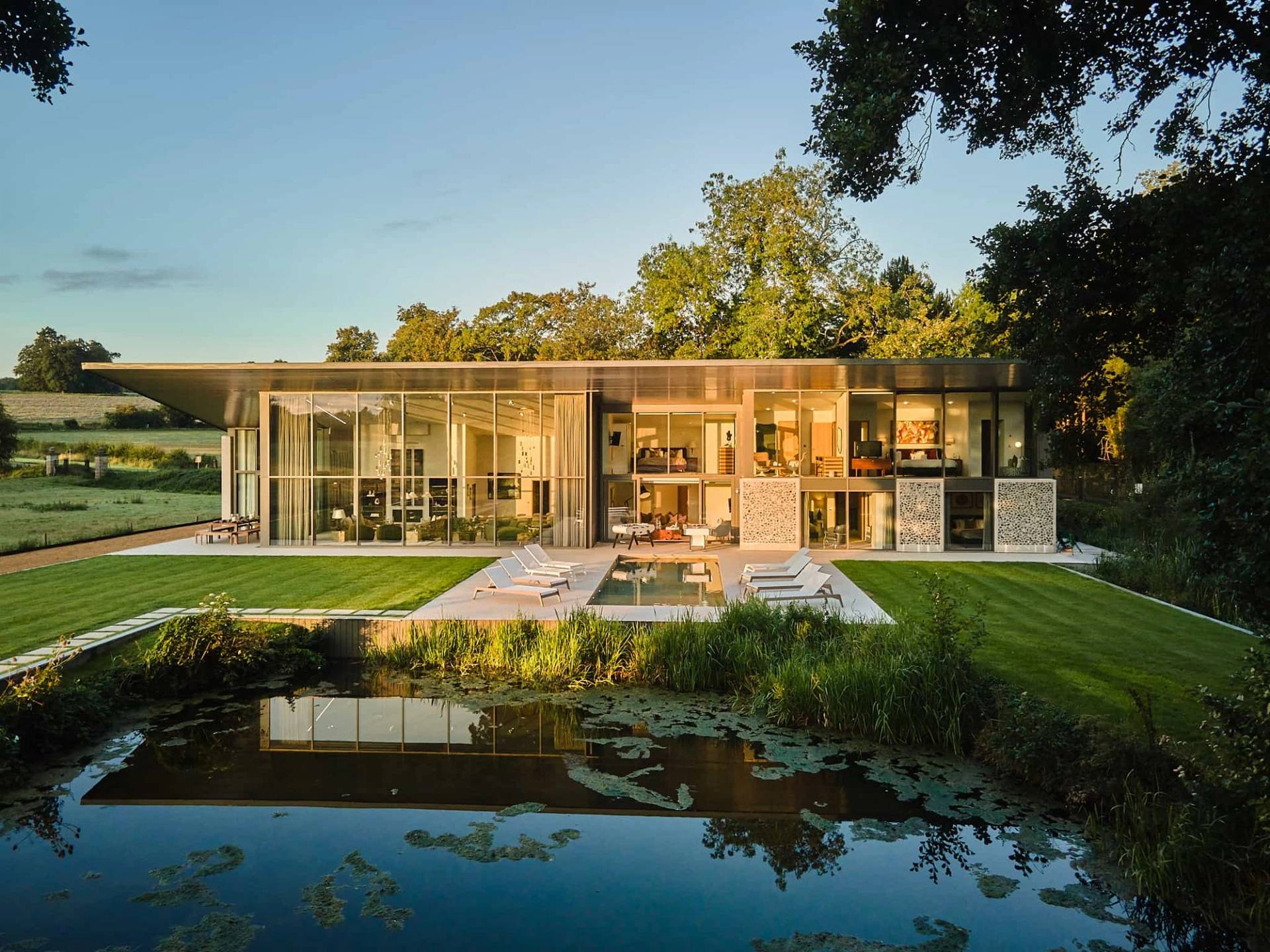 Contemporary glass mansion shoot location in Winchester, SO21 featuring a double-height glass facade, luxury bedroom suites, home gym, outdoor swimming pool, and private lake grounds, the ultimate high-visibility backdrop for feature film productions, TV commercials, automotive brand campaigns, and commercial photography via Love Locations.