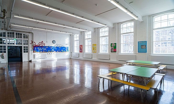 Primary school dining hall and multi-use space with folding lunch tables and large multi-paned windows, Love Locations N4.