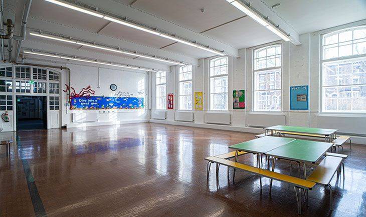 Primary school dining hall and multi-use space with folding lunch tables and large multi-paned windows, Love Locations N4.