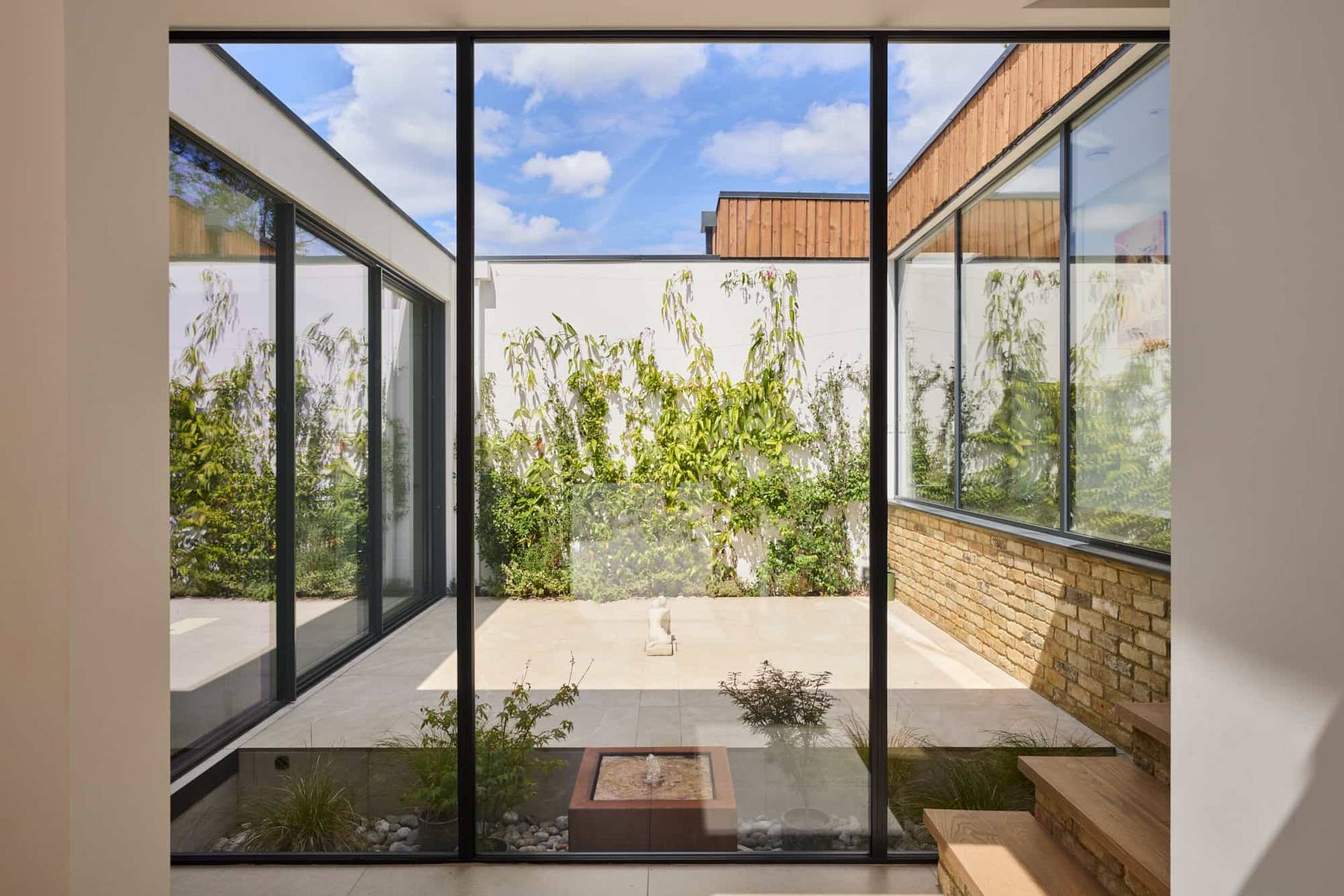 Internal glass courtyard surrounded by floor-to-ceiling windows, yellow brick walls, and central zen garden planters, perfect for high-fashion lookbooks, Love Locations KT22.