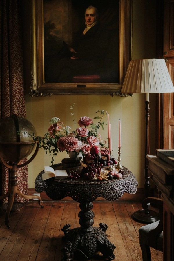 Antique table vignette with brass globe, floral bouquet, and soft lamp lighting in a castle, Love Locations KY15.