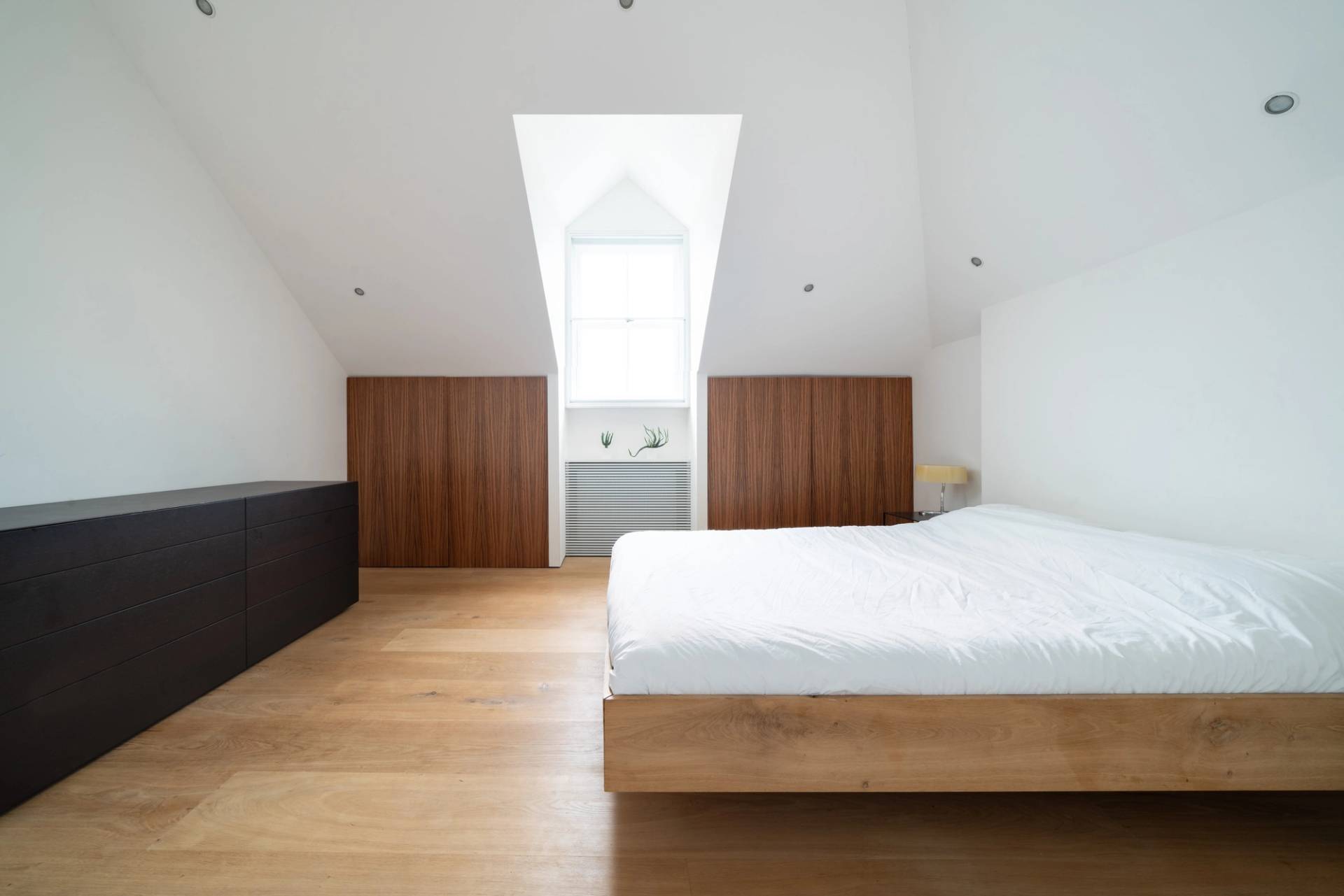 Spacious bedroom suite featuring a low wooden bed, neutral walls, and sash window light, Love Locations SW6.