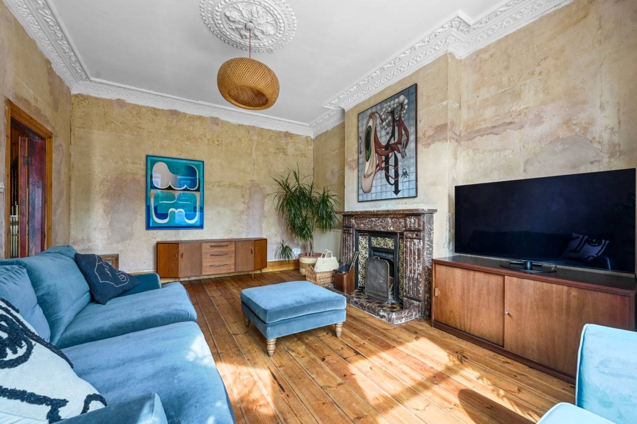 Spacious double reception room with plaster walls, blue corner sofa, and vintage artwork in Newham, E7, ideal for lifestyle editorial shoots, Love Locations.