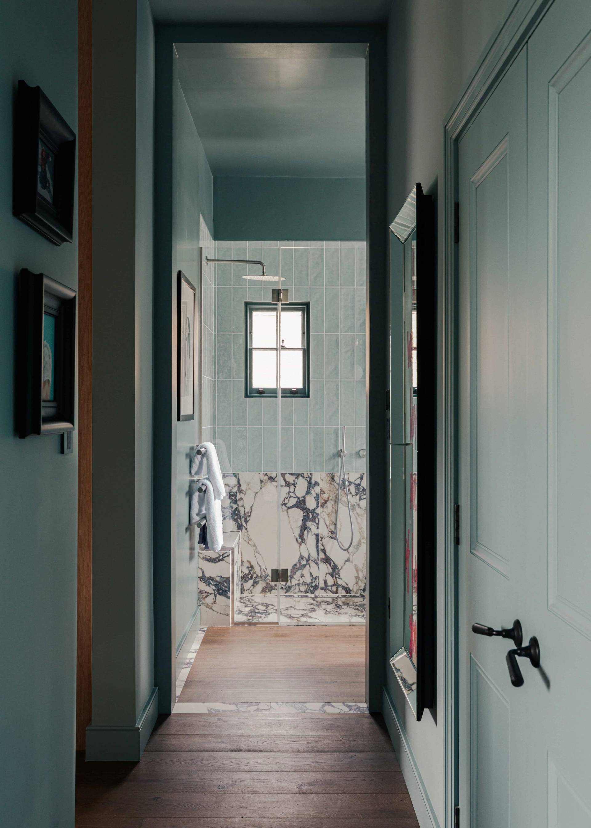 Ensuite bathroom transition looking past teal doors into a marble-tiled walk-in shower room, Love Locations.