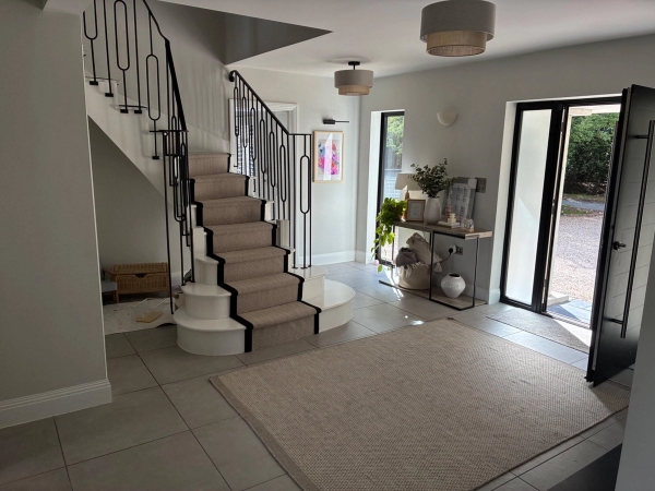Elegant hallway staircase location house in Essex CM4 through Love Locations, highlighting a curved carpeted staircase, wrought iron banisters, and high ceilings.