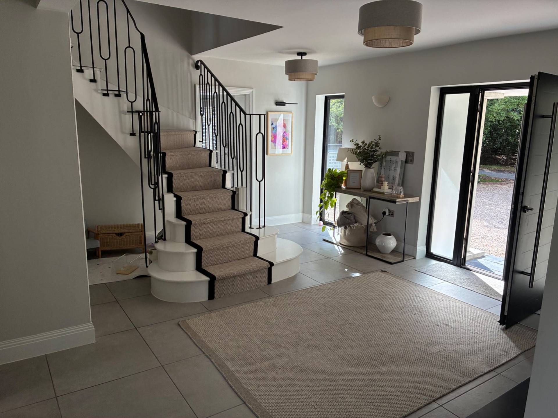 Elegant hallway staircase location house in Essex CM4 through Love Locations, highlighting a curved carpeted staircase, wrought iron banisters, and high ceilings.