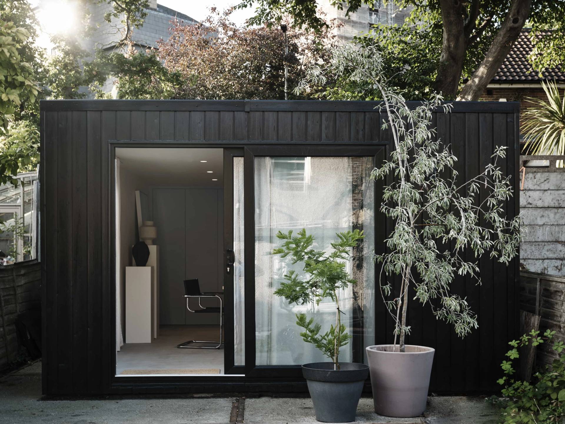 Modern black timber garden office pod set against lush green foliage in an East London location home, Love Locations E4.