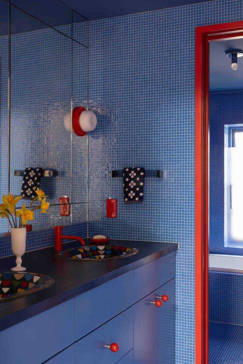 Vibrant blue mosaic tiled bathroom vanity shoot venue in a Boerum Hill townhouse via Love Locations, with red trim accents and a blue countertop.