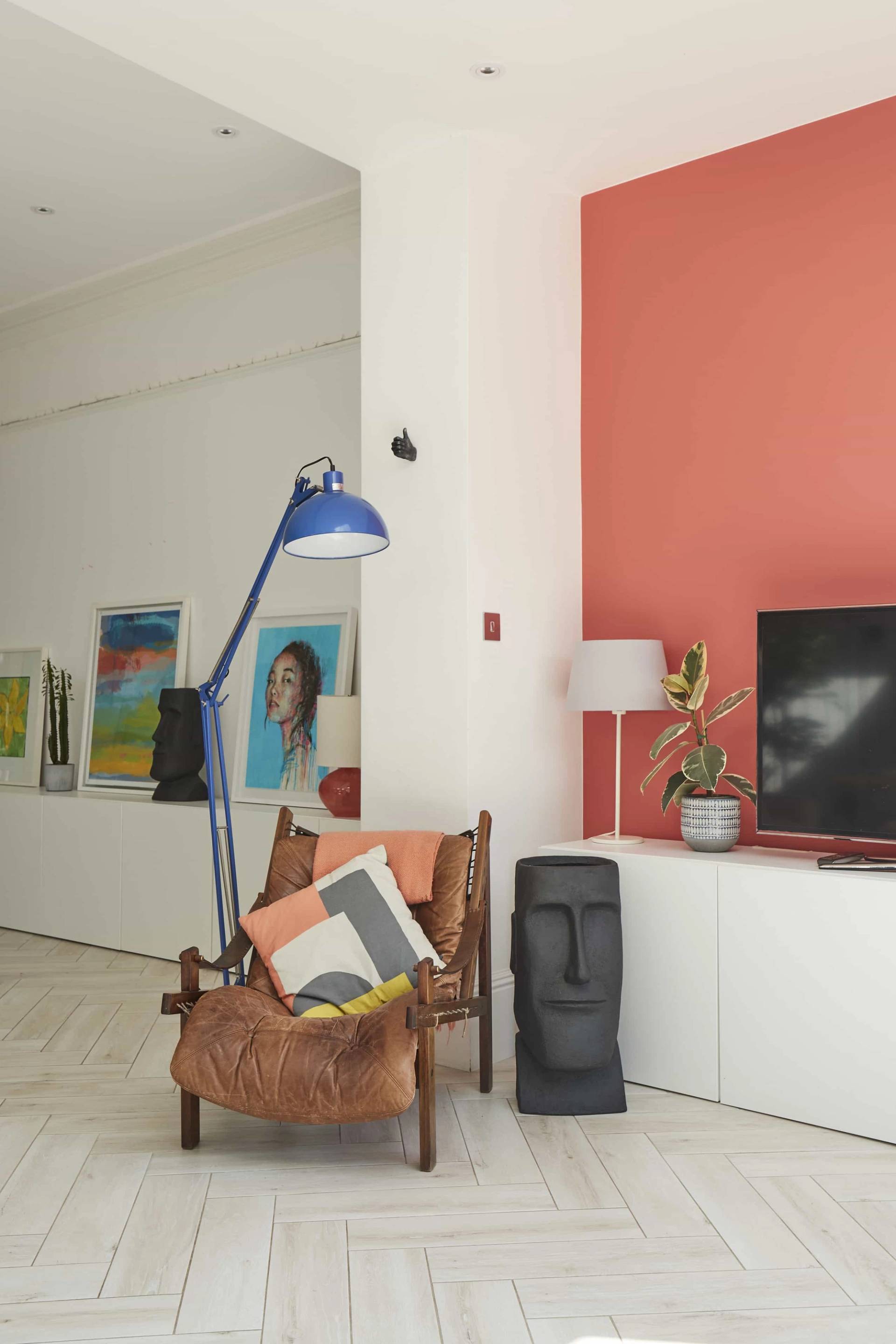Cozy reception nook with coral accent wall, brown leather armchair, blue anglepoise lamp, and modern artwork, Love Locations Ealing Common.