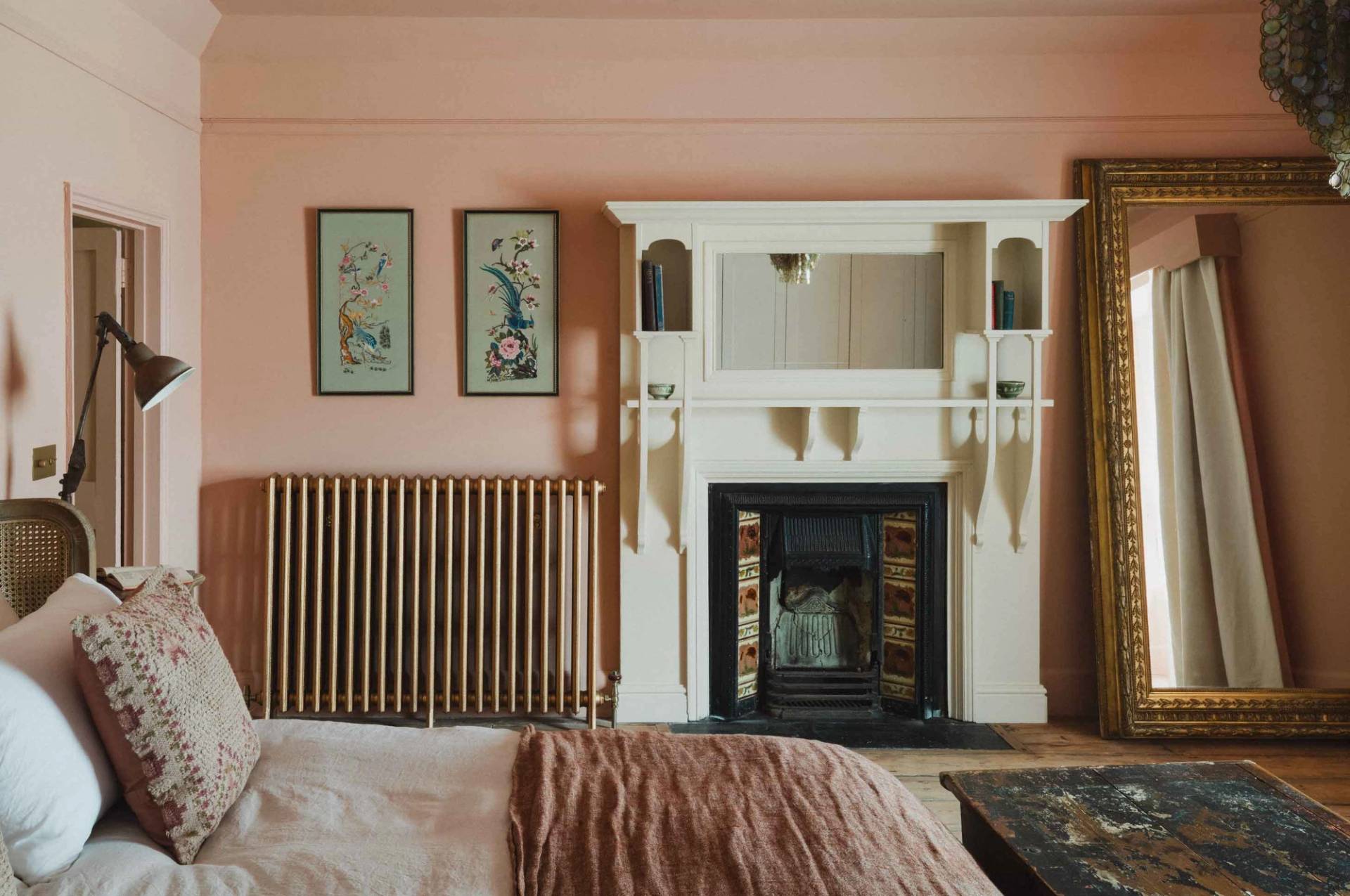 White ornate fireplace mantel and cast-iron insert in a pink bedroom photoshoot location through Love Locations.