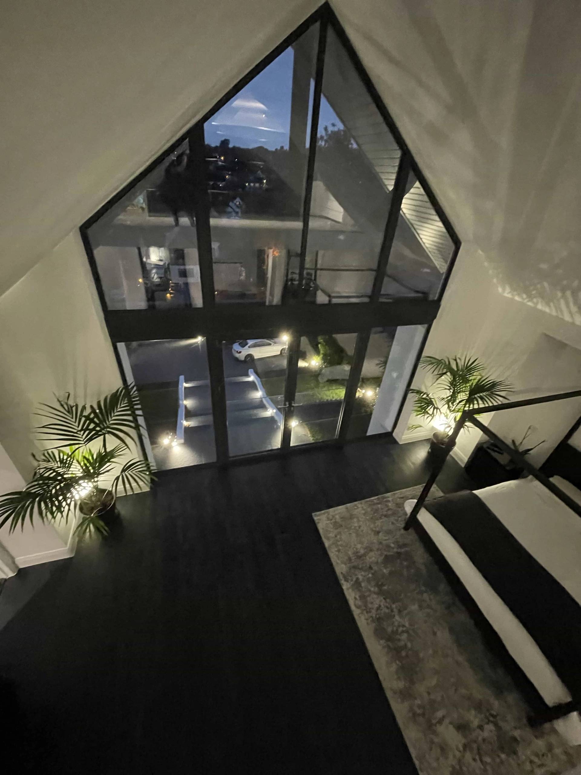 High-angle view looking down through double-height A-frame glass windows onto an outdoor entrance terrace, Love Locations IG10.
