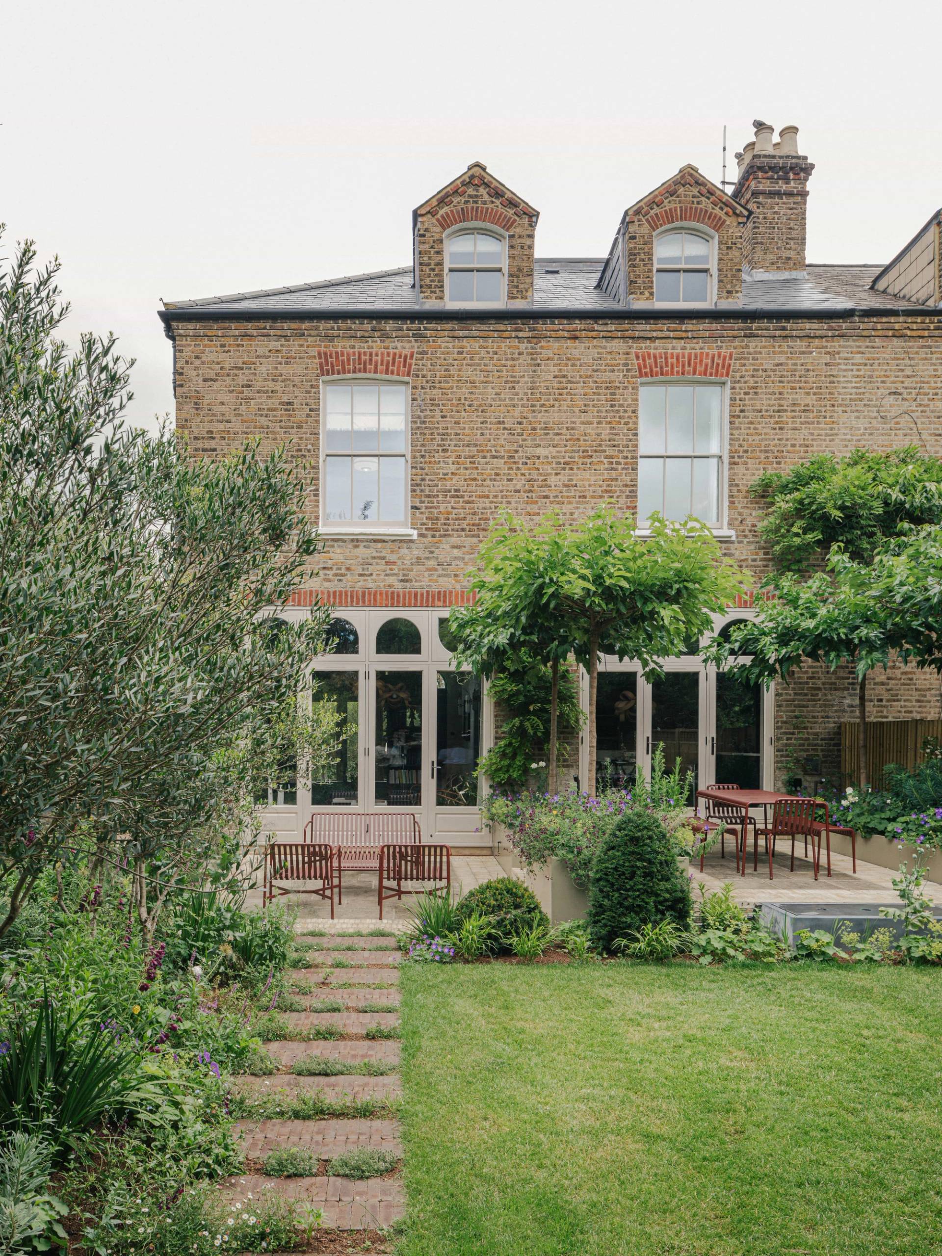 Rear elevation of a Victorian brick villa showing arched french doors and a manicured lawn garden, ideal for TV drama filming, Love Locations SW13.