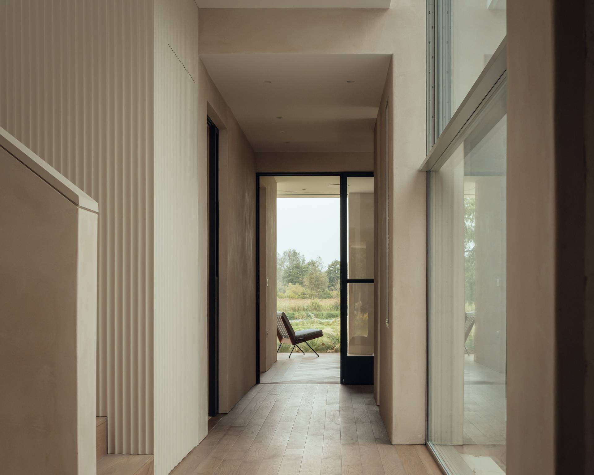 Long minimalist corridor featuring fluted plaster wall panelling, micro-cement floors, and glass patio doors, perfect for luxury lifestyle campaigns, Love Locations.