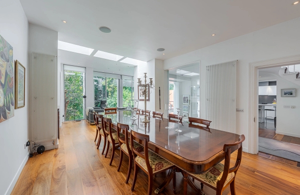 Grand wooden dining table setup surrounded by matching chairs and bathed in natural light from large windows, perfect for luxury lifestyle advertising, Love Locations.
