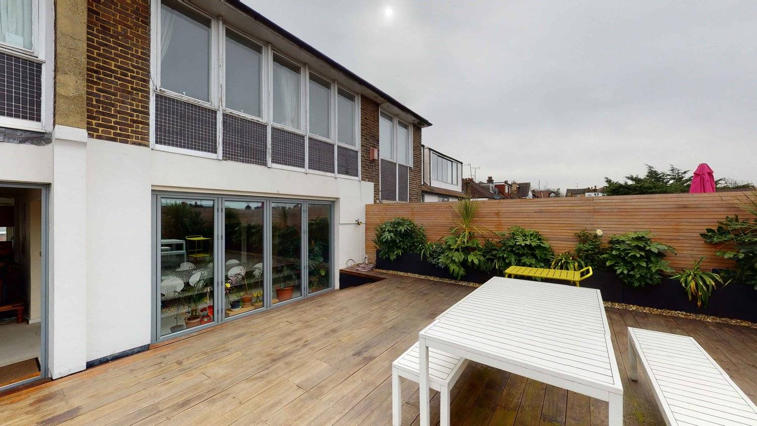 Spacious outdoor roof deck terrace featuring white bench seating, timber fence privacy screen, and planters, Love Locations SW16.