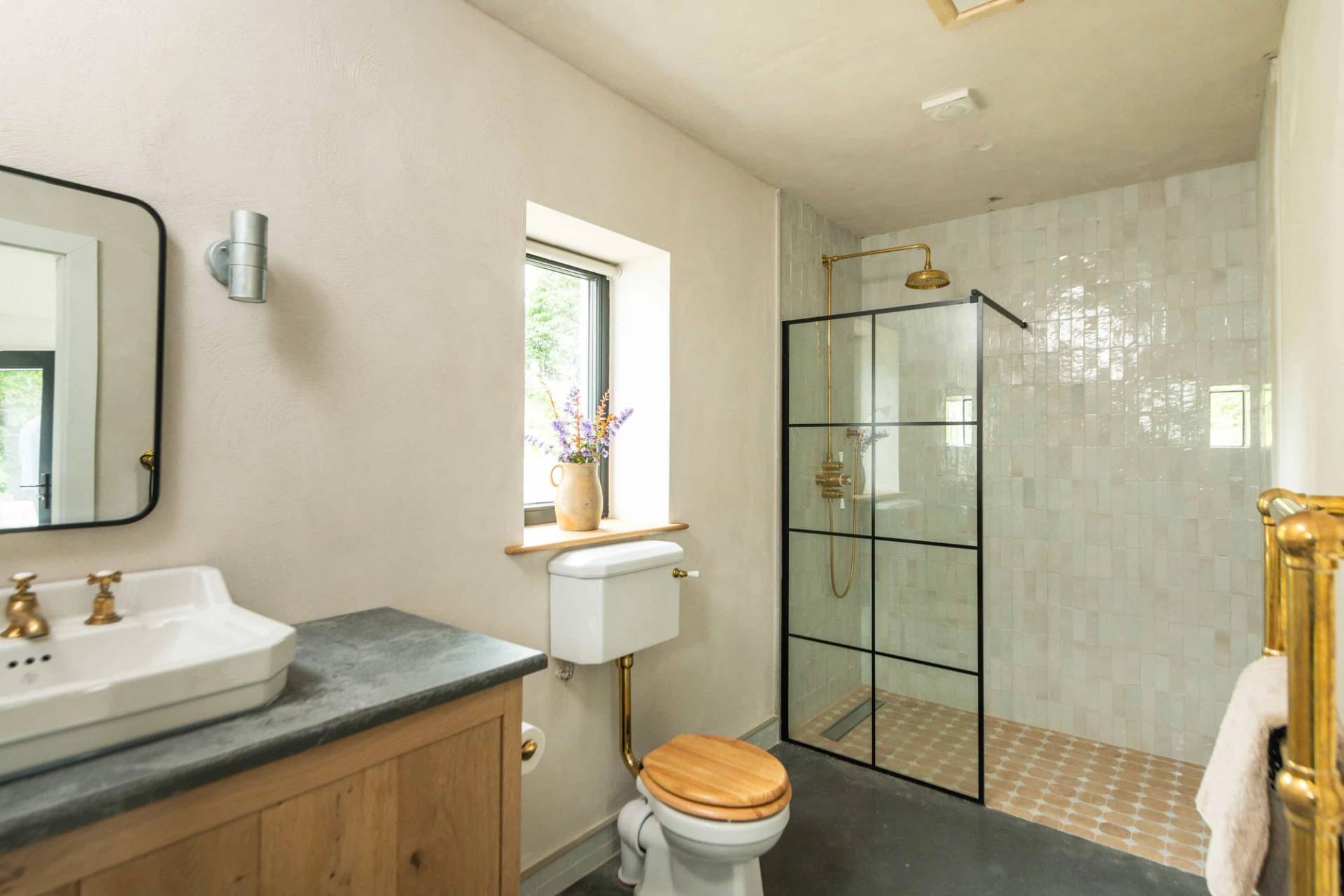 Modern en-suite bathroom film location in Castleblayney County Monaghan Ireland by Love Locations, featuring a glass walk-in shower, black grid frame, and wooden vanity unit.