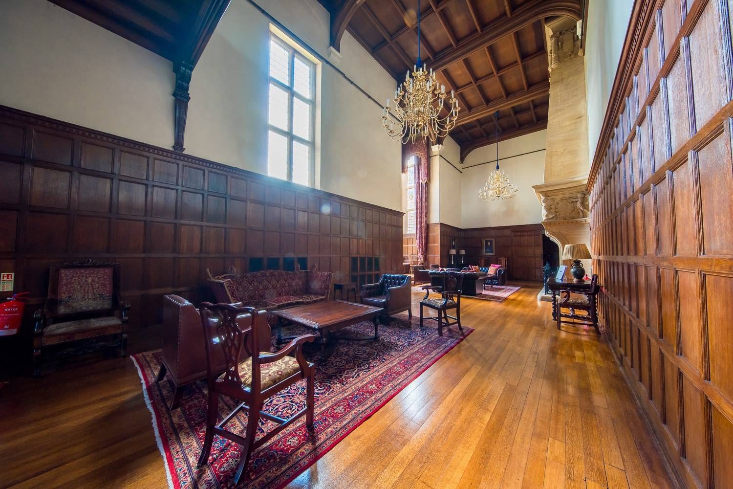 Atmospheric wood-panelled reception hall with vintage armchairs and rug in a historic Hertfordshire filming venue by Love Locations.