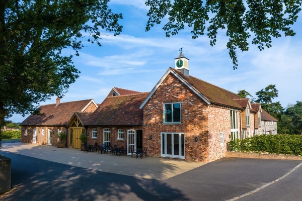 Charming brick courtyard buildings and traditional clock tower at Greentrees country estate, premium event venue by Love Locations.