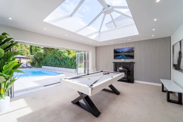 Bright entertainment space with a pool table, wall-mounted TV, and glass lantern roof skylight, Love Locations RM11.