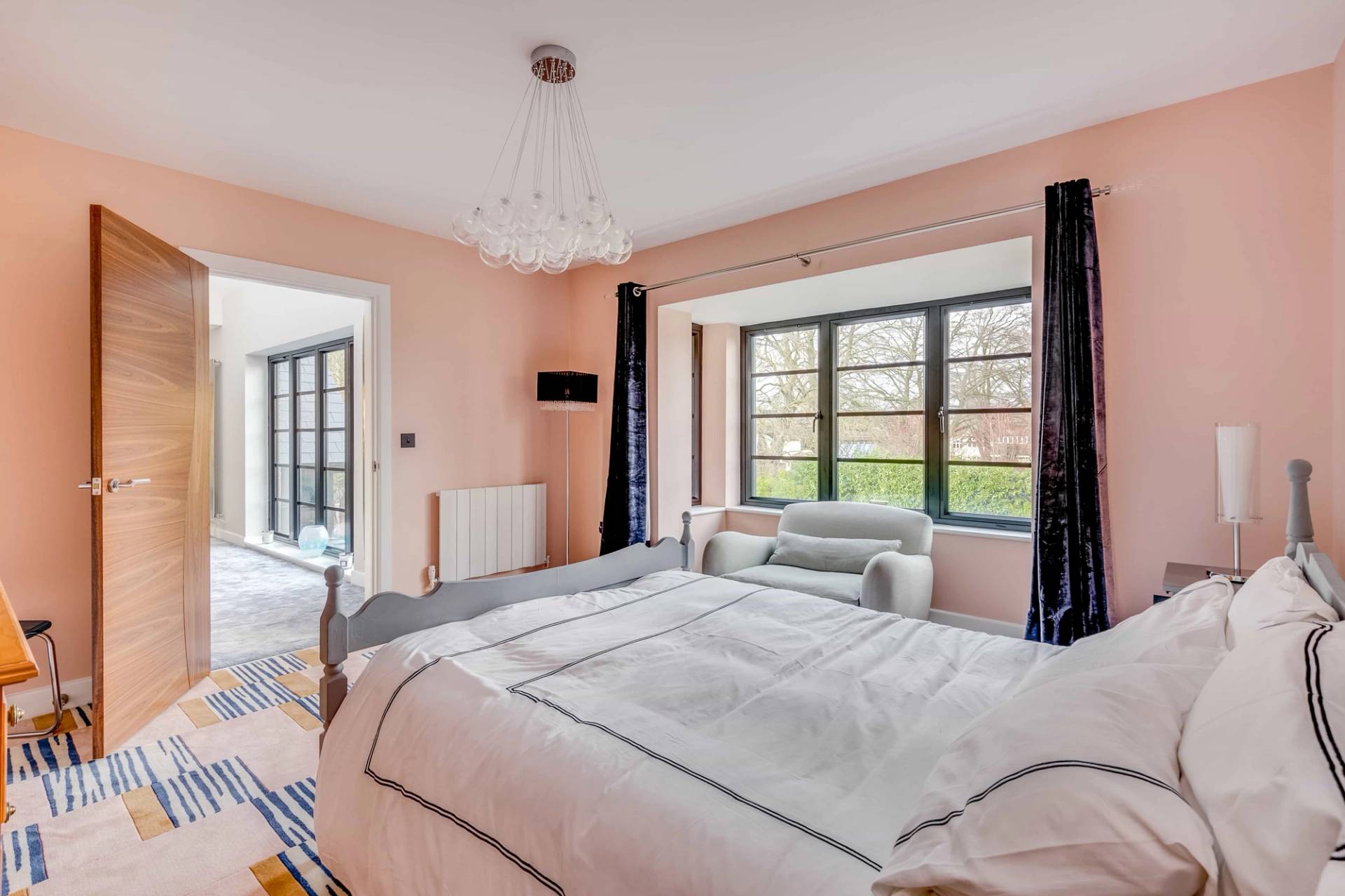 Pastel bedroom featuring a grey bed, blush walls, and sash window light, ideal for lifestyle editorial shoots, Love Locations CB2.