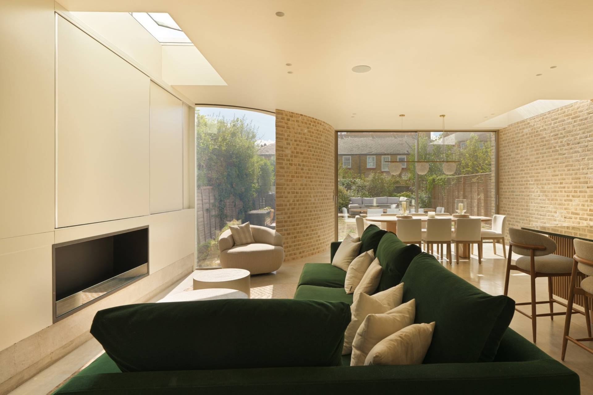 Sunlit reception room shoot space featuring a deep forest green L-shaped sofa, roof skylights, and floor-to-ceiling glass doors through Love Locations.