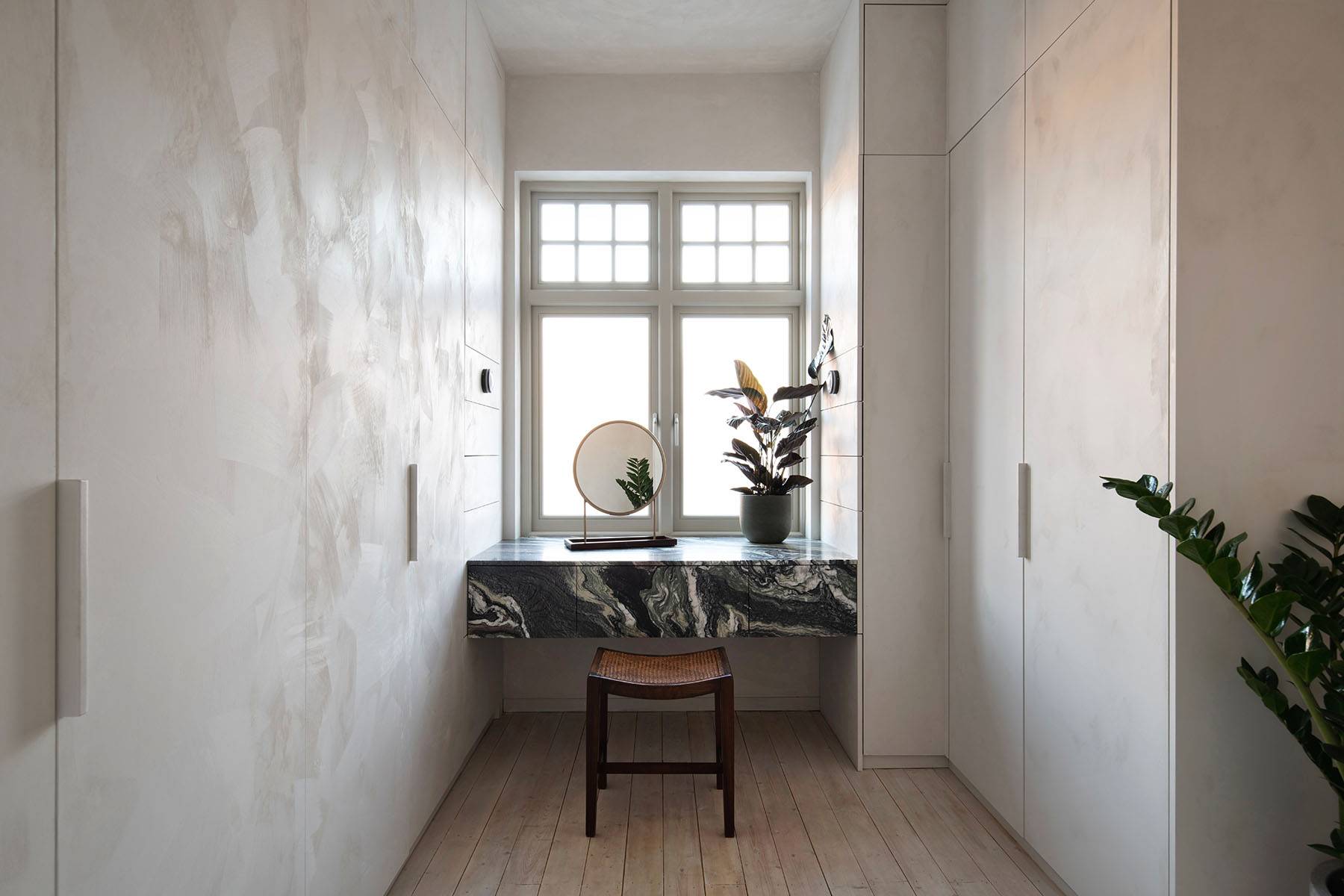 Close-up detail of a dark-veined marble vanity counter set in a bright micro-cement dressing room, Love Locations.