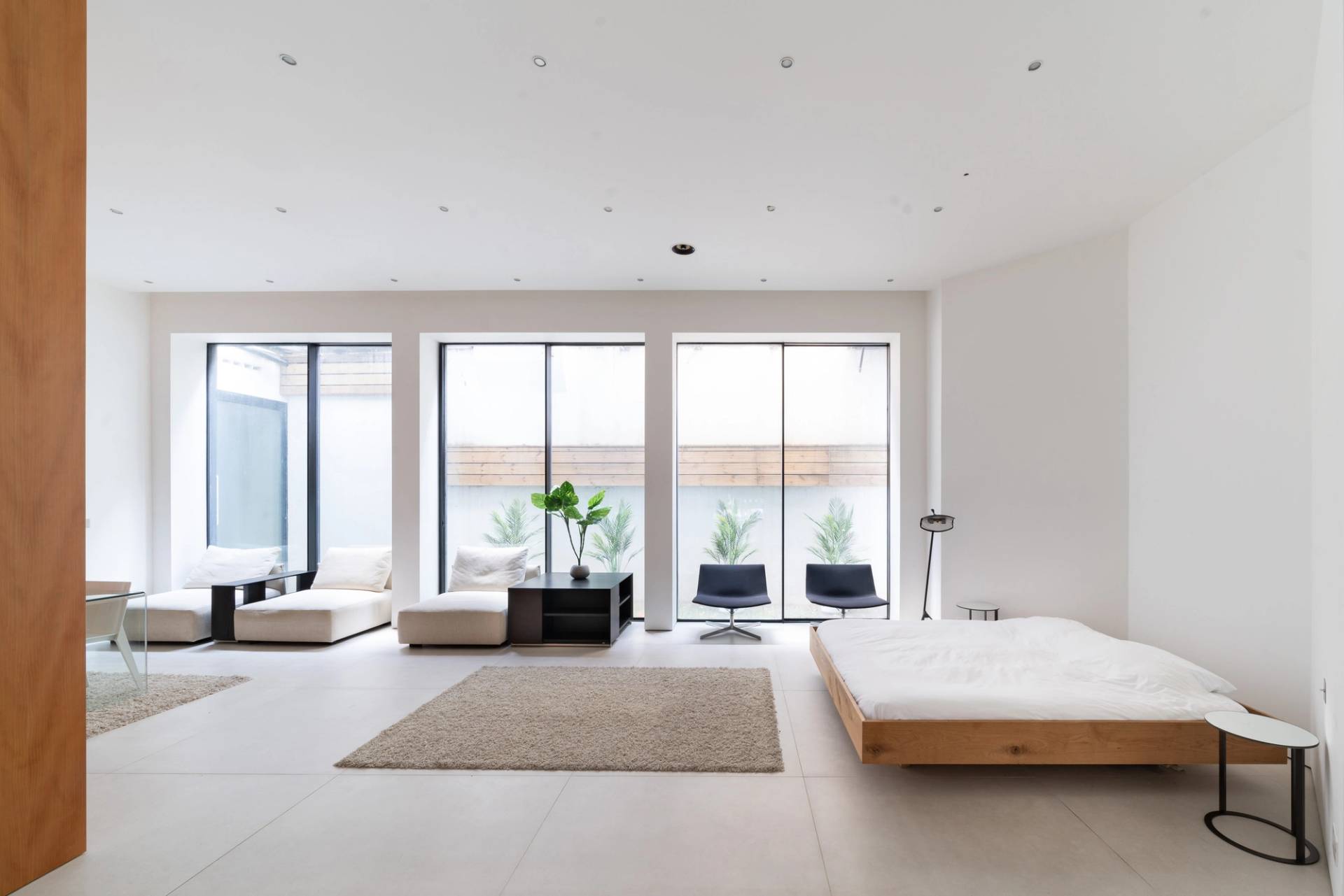 Sunlit open-plan seating room featuring low platform sofas, floor-to-ceiling windows, and area rugs, Love Locations SW6.