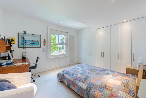 Minimalist guest bedroom space featuring clean white built-in wardrobes and an integrated work-from-home desk setup, perfect for remote worker ads, Love Locations.