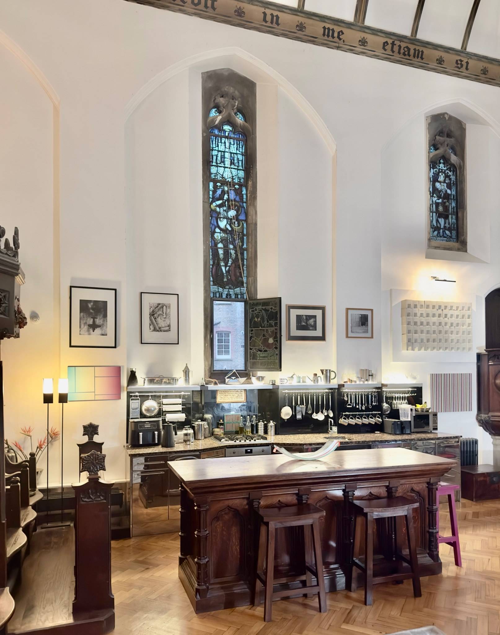 Open-plan kitchen area in a period chapel conversion photoshoot location in Oval SE5 via Love Locations, featuring stainless steel worktops and stained glass windows.