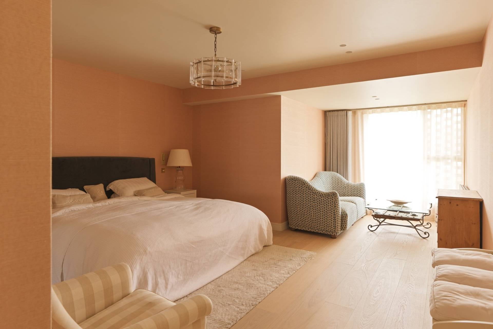 Warm terracotta-toned bedroom shoot space featuring a king-sized bed, soft pendant light, and plush carpet via Love Locations.