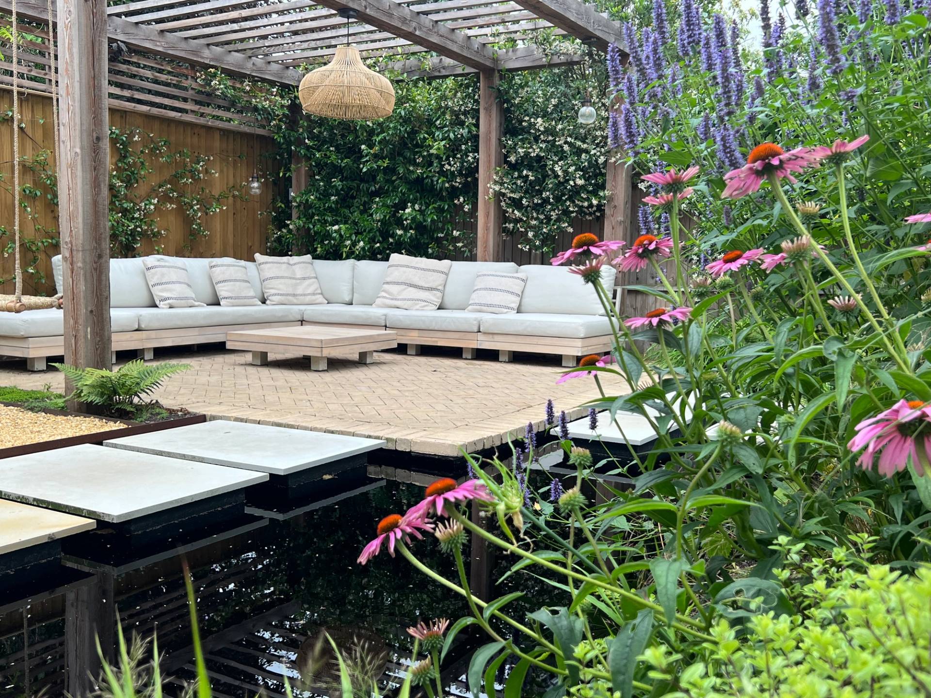 Landscaped garden patio featuring a modern water feature pond, stepping stone path, and pergola seating, Love Locations TW1.