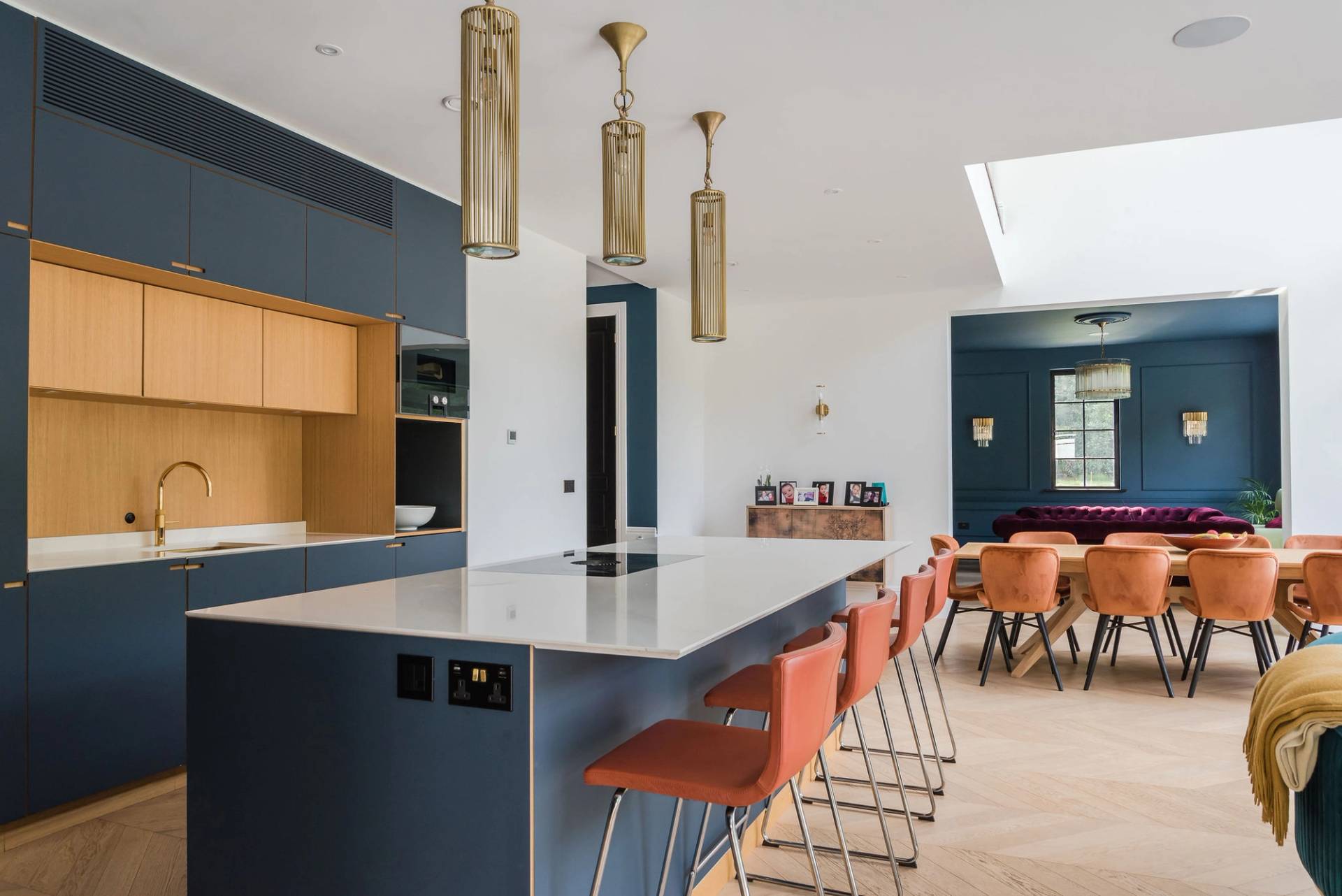 Dark blue kitchen island with white marble countertop, gold pendant lights, and rust-orange velvet bar stools, ideal for culinary ad shoots, Love Locations GU3.
