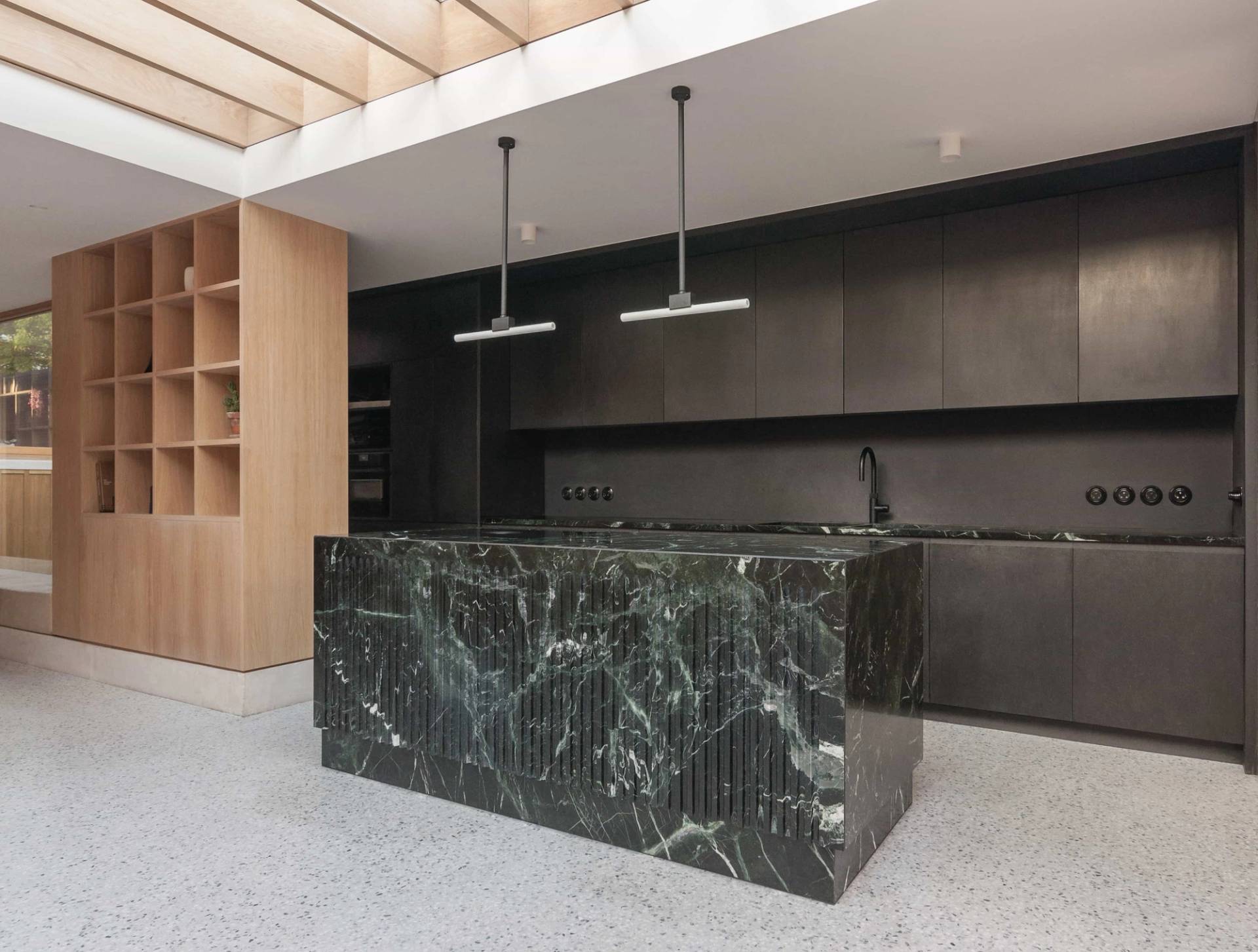 Luxury modern kitchen photoshoot location in Hackney London N16 from Love Locations, featuring a dramatic green marble island counter, dark minimalist cabinets, and exposed timber roof rafters.