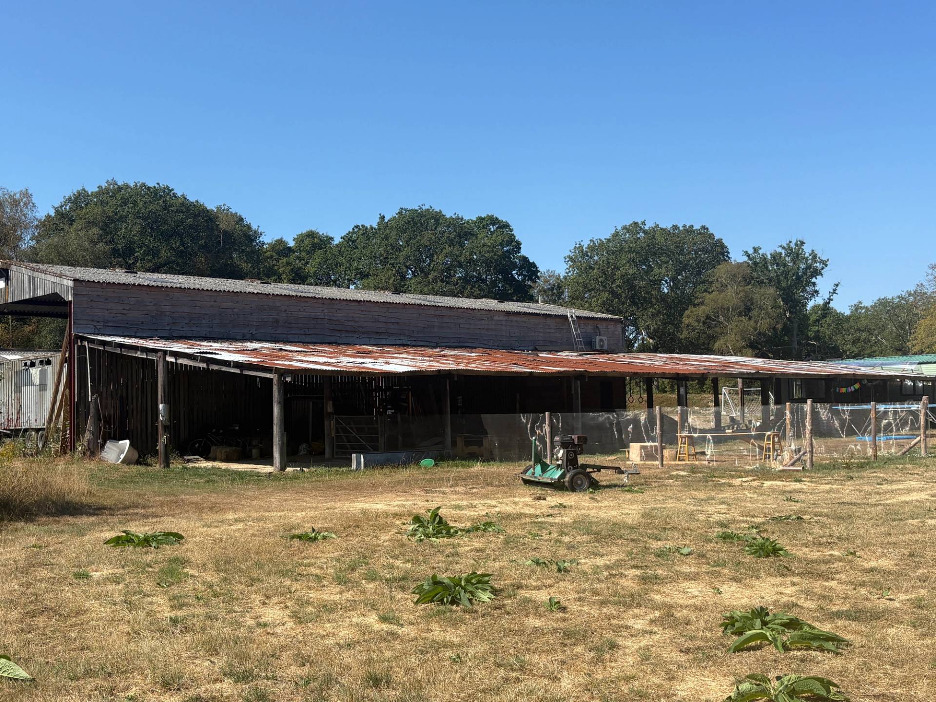 Industrial farm location in South Chailey, BN8 featuring open timber barn shelters, dry grass fields, and corrugated metal outbuildings via Love Locations.