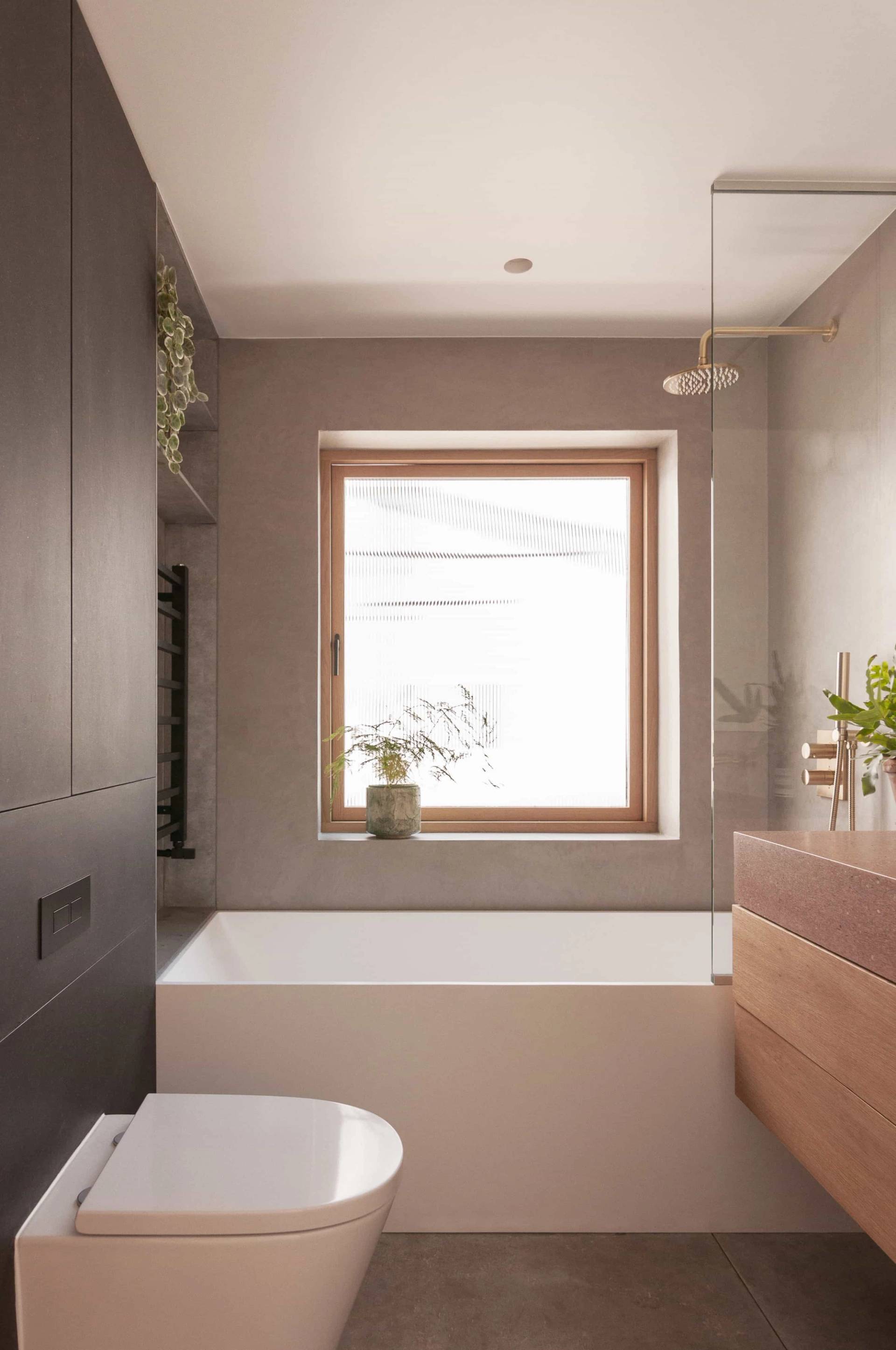 Sunlit master bathroom film location with a deep soaking bathtub and square picture window in Hackney N16 via Love Locations.