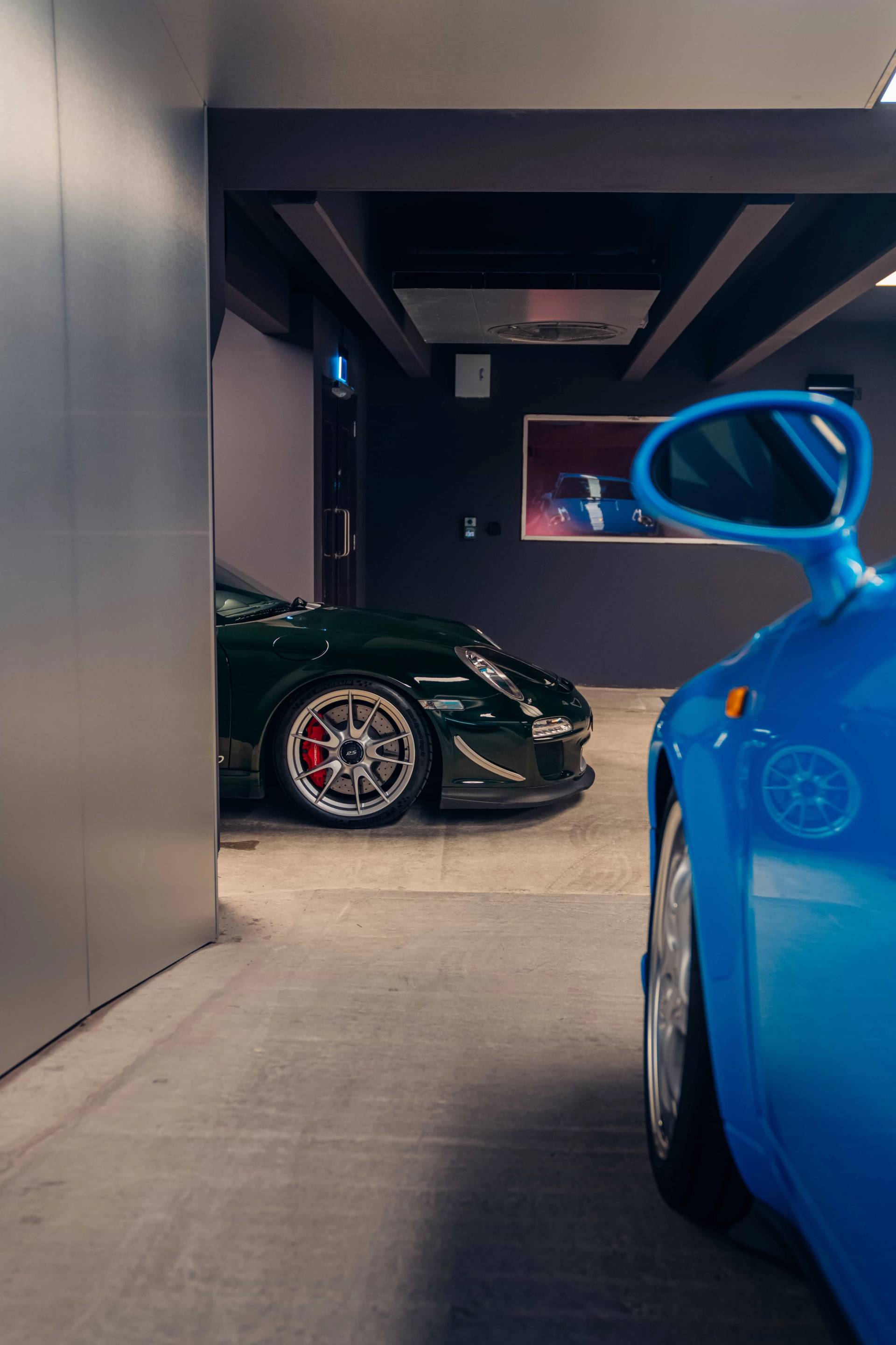 Sleek blue sports car framed by dark concrete walls and entrance doorways in a Brentford TW8 bunker location from Love Locations.