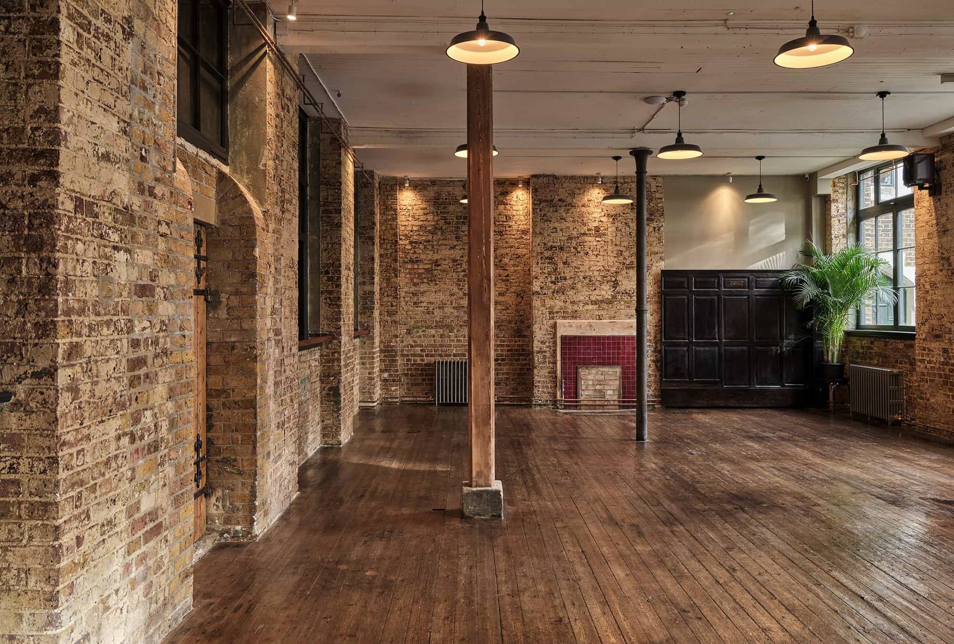Industrial hall view showing exposed brickwork, wooden support pillars, and large windows, perfect for fashion editorial shoots, Love Locations.
