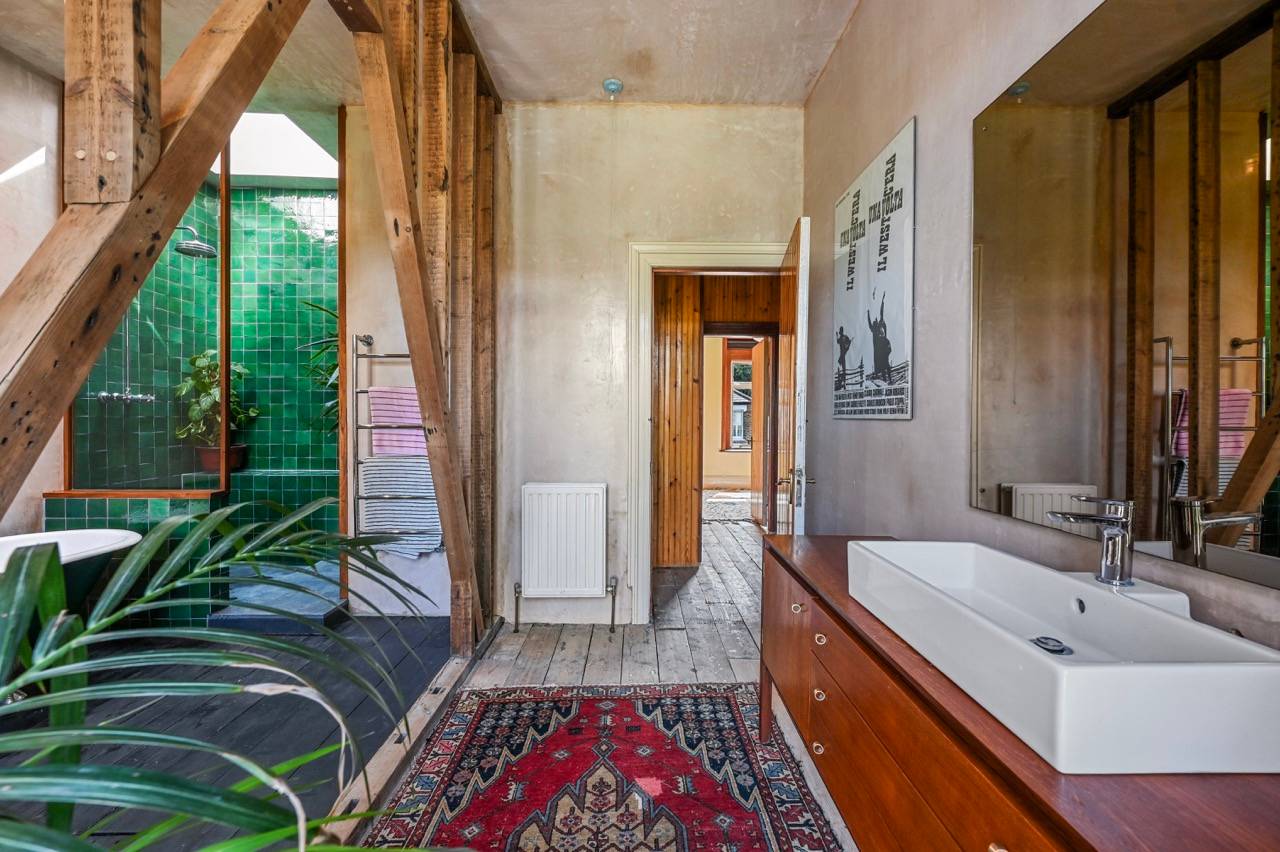 Dressing room corner with dark wood floorboards, red oriental rug, and mid-century timber vanity, Love Locations E7.