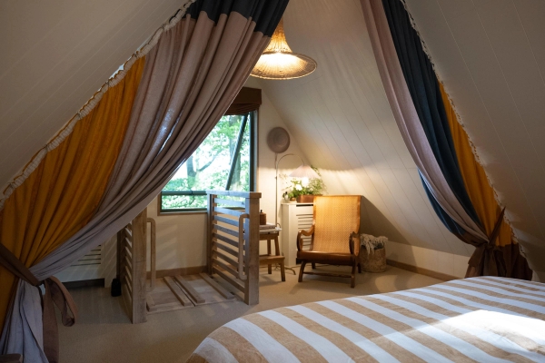 Looking out from a cozy loft bed platform down toward a rustic armchair reading nook, unique architectural filming perspective via Love Locations.