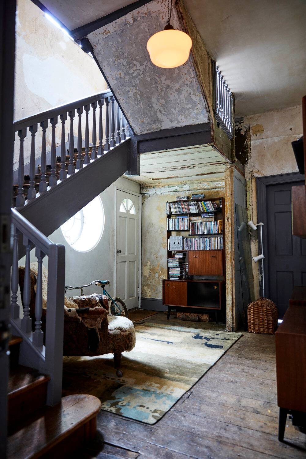 Character hallway passage with exposed timber stairwell, bookcase, and retro armchair, Love Locations SE8.