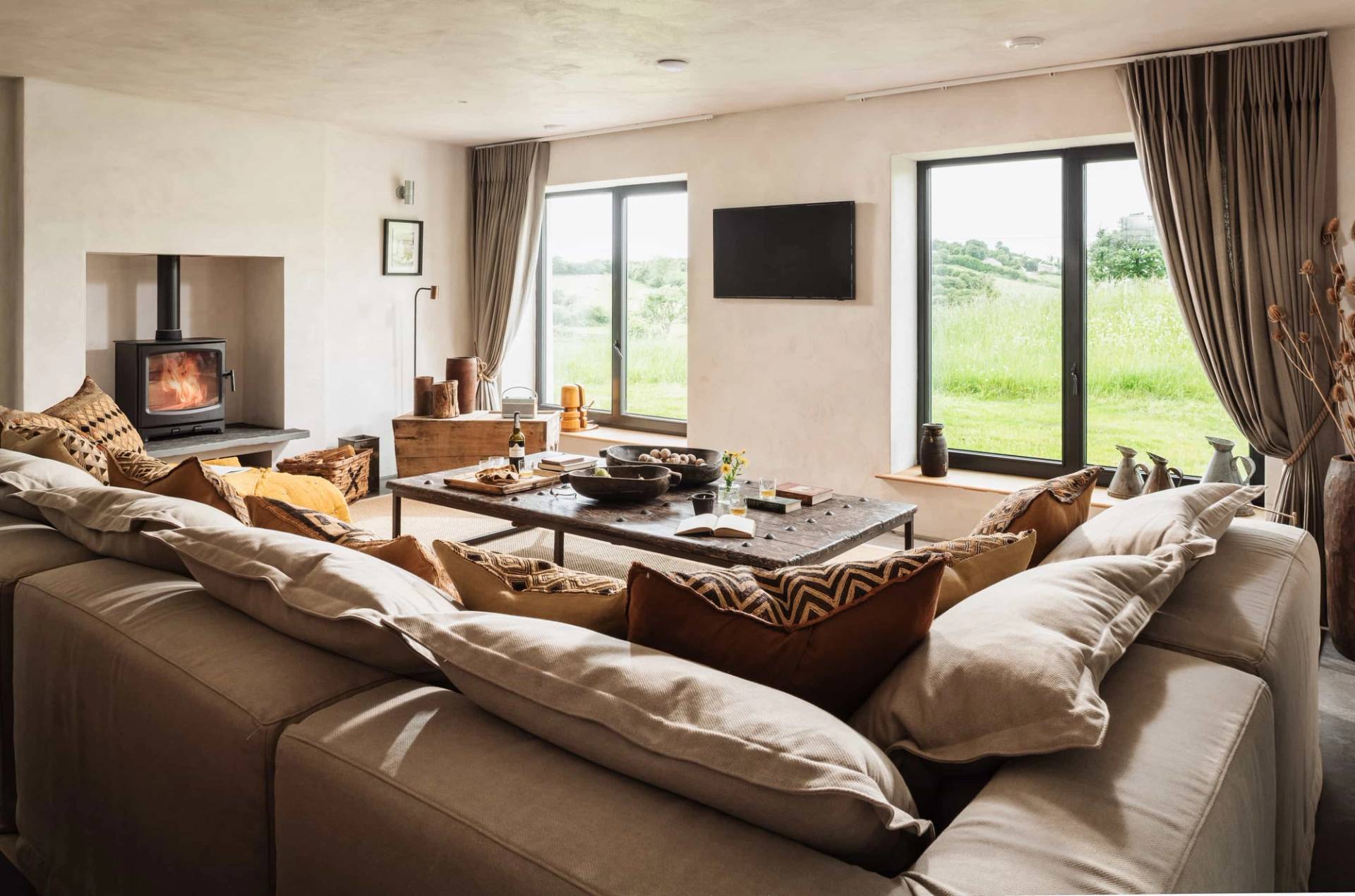 Modern rustic lounge shoot space in Castleblayney County Monaghan Ireland via Love Locations, with plush sofas, low coffee table, and large black-framed picture windows.