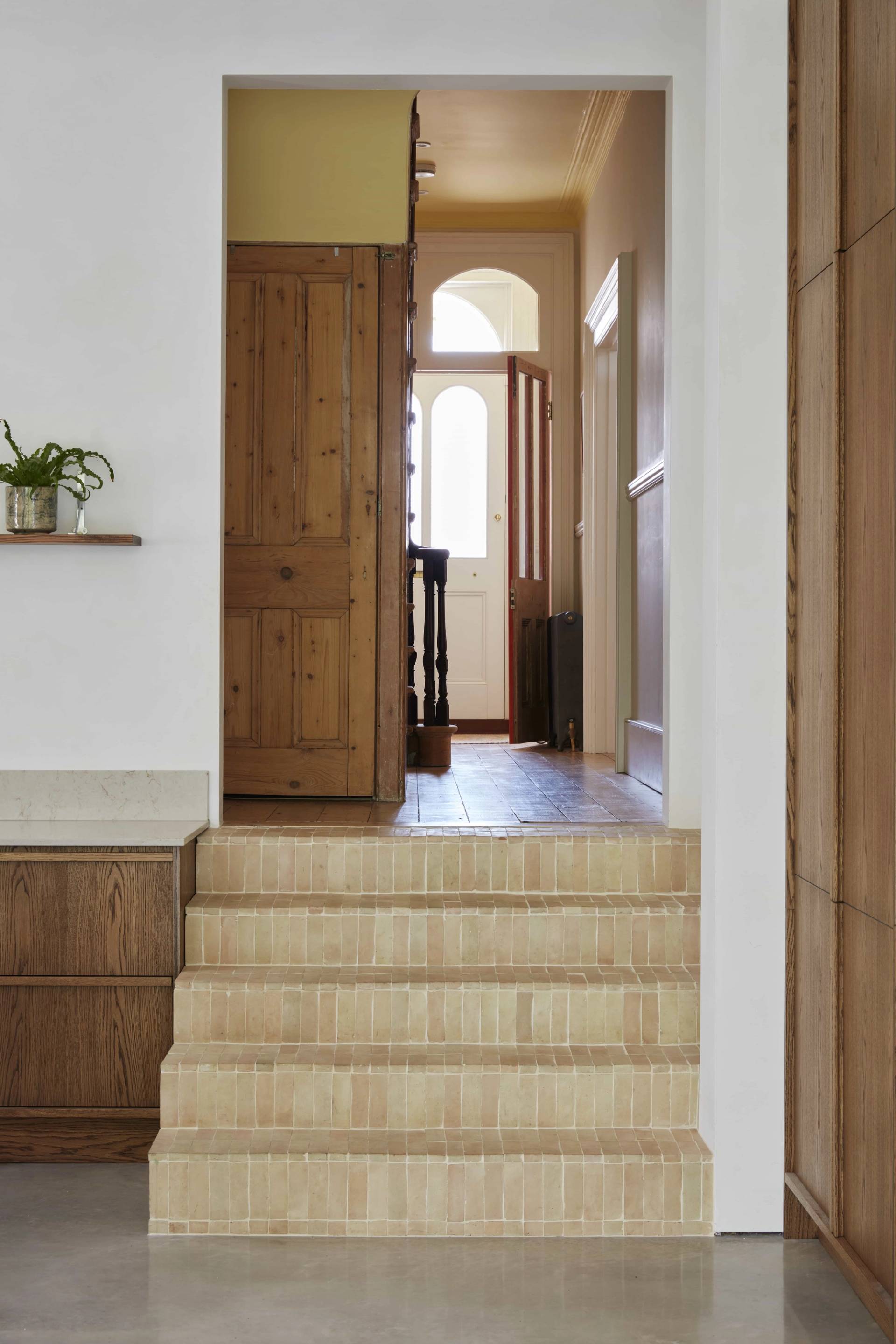 Character stairwell passage showing raw wood steps, an open doorway, and period archways, perfect for film establishing shots, Love Locations.
